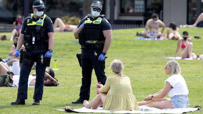 Police officers walk among beachgoers at St Kilda to ensure they are wearing masks and obeying distancing rules. Picture: NCA NewsWire / David Geraghty