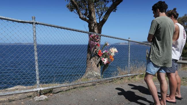 Two boys known to the late Maggie Lore, who tragically fell from the Blackmans Bay cliffs on Saturday evening, reflect at a floral tribute near where the accident occurred. Picture: LUKE BOWDEN