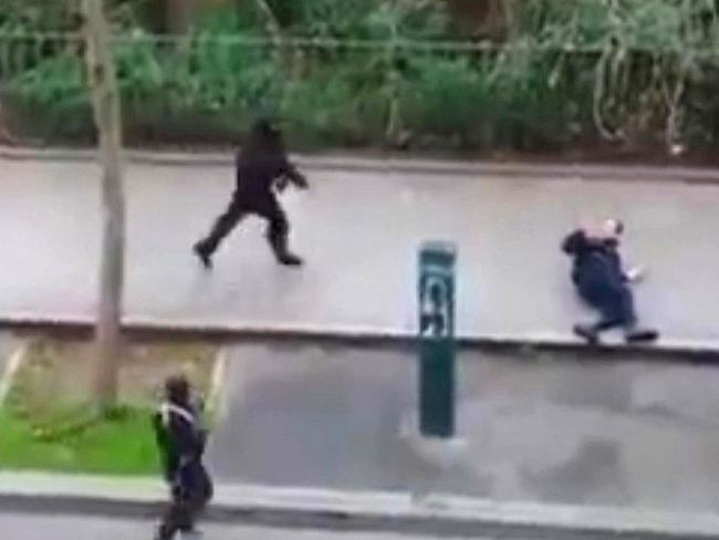 Masked gunman run towards a victim of their gun fire outside the French satirical newspaper Charlie Hebdo's office, in Paris. (AP Photo) NO SALES