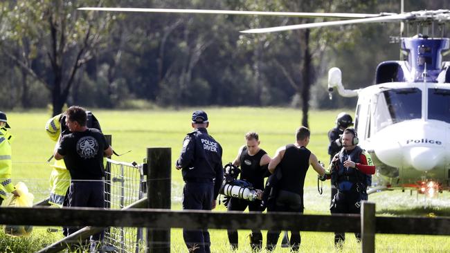 Police divers return on PolAir after recovering the body of a man trapped in a vehicle submerged in flood water on Cut Hill Road at Cobbitty. Picture: Jonathan Ng