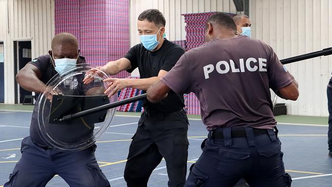 China Police Liason Team officer (C) training local Solomon Islands officers in drill, unarmed combat skills, advanced usage of long sticks, basic rifle tactics and crowd control. Picture: AFP.