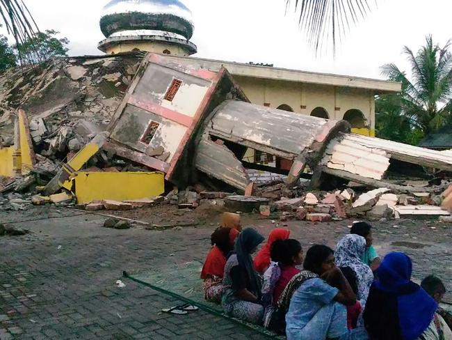 Residents gather outside a damaged mosque, its minaret reduced to rubble following its collapse in the town of Pidie, Indonesia's Aceh province. Picture: AFP