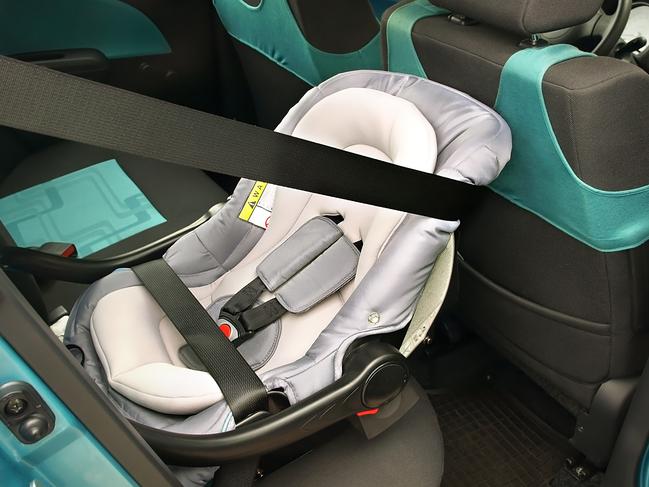 A rear-facing baby seat properly installed in compact car.