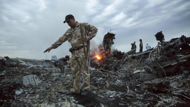 People walk amongst the debris at the crash site of MH17 passenger plane near the village of Grabovo, Ukraine in 2014. Picture: AP