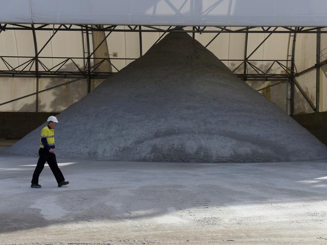 A worker walks past a pile of lithium ore at a Talison Lithium Ltd. site, a joint venture between Tianqi Lithium Corp. and Albemarle Corp., in Greenbushes, Australia, on Thursday, Aug. 3, 2017. Rising Chinese demand for lithium-ion batteries needed for electric vehicles and energy storage is driving significant price gains and an asset boom in Australia, already the world's largest lithium producer. Photographer: Carla Gottgens/Bloomberg