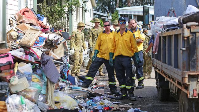 Volunteers, including from the RFS and ADF 6th Battalion RAR, tackle the mess. Picture: Nathan Edwards