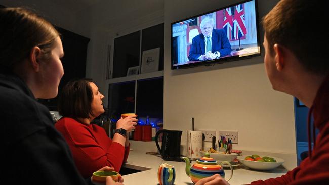 A family gather around the television in Liverpool, north west England to watch Britain's Prime Minister Boris Johnson give a televised message to the nation from Downing Street.