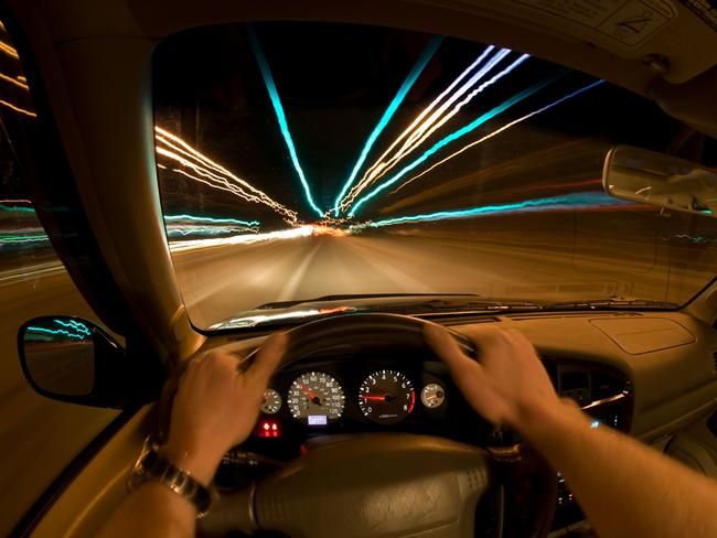 Night Speeding. Motorist behind wheel of car.