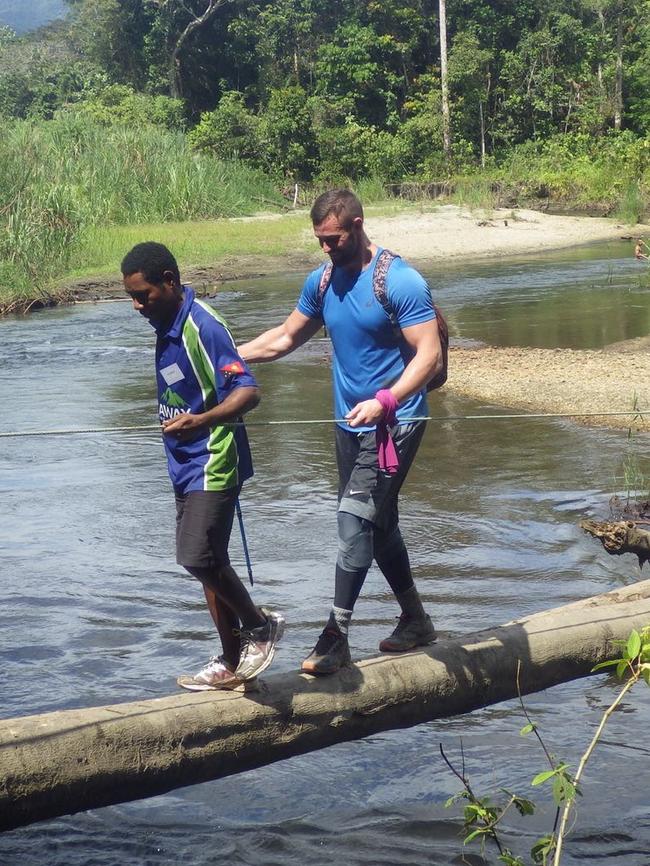 With a guide crossing a river along the Kokoda Trail. Picture: Supplied