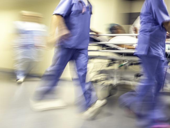 Doctors and nurses pulling hospital trolley,