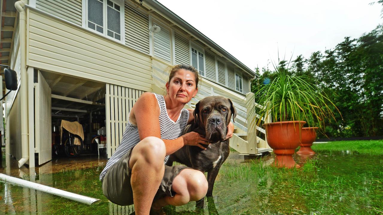 Tori Walker stands out the front of her flooded Queens Road home in Railway Estate with dog Tia, 5. Picture: Zak Simmonds