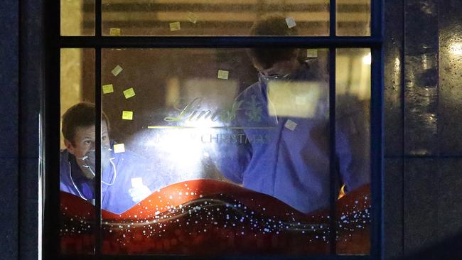 A tribute wall has been established at Elizabeth Street and Martin Place with flowers and cards being laid throughout the night. Forensic services could be seen working inside the Lindt Cafe, marking shotgun pellet marks on windows. Police Rescue Squad taped up black plastic on the outside of the cafe windows to block the view into the cafe. Pics Bill Hearne