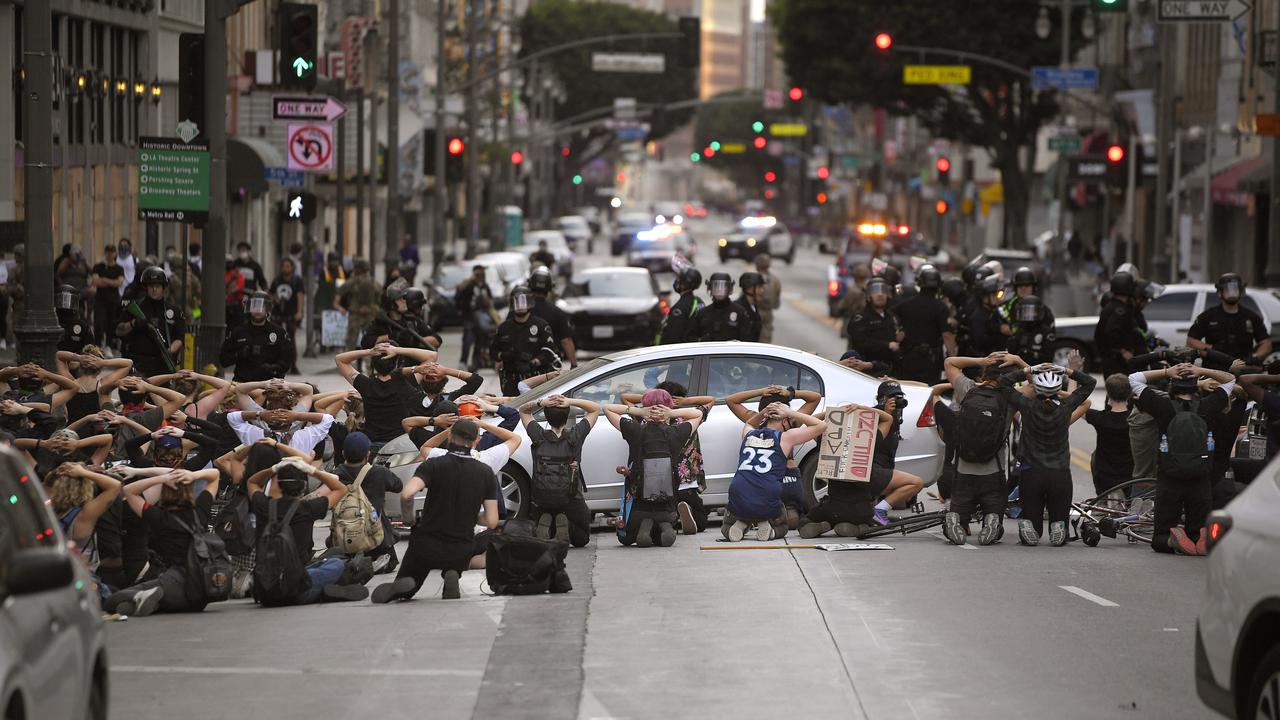 Demonstrators put their hands behind their heads before being taken into custody after the city's curfew went into effect following a protest in Los Angeles over the death of George Floyd. Picture: AP/Mark J Terrill