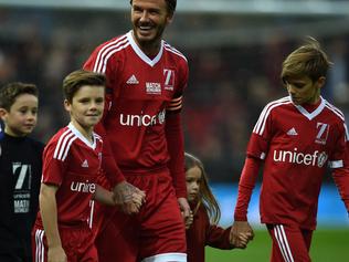 GB and Ireland's English captain David Beckham (C) and Rest of the World's Portuguese captain Luis Figo (L) lead their teams out ahead of a charity football match between a Great Britain and Ireland team and a Rest of the World team at Old Trafford in Manchester, north west England November 14, 2015 in aid of UNICEF. AFP PHOTO / PAUL ELLIS