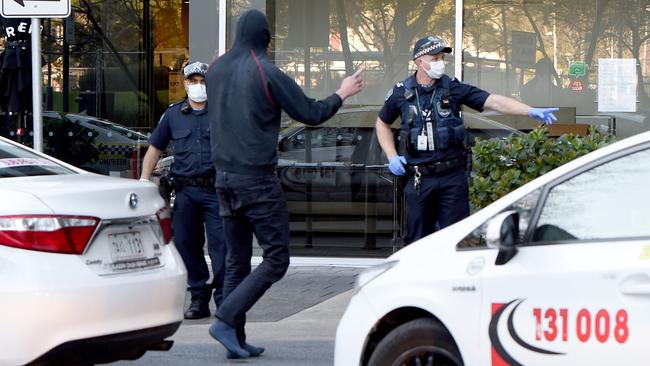 Police in masks take one of the stowaways into the Pullman Hotel for quarantine. Picture: NCA NewsWire / Naomi Jellicoe