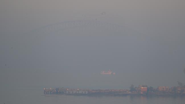 The Sydney Harbour Bridge is only just visible as thick smoke blankets Sydney. Picture: John Grainger