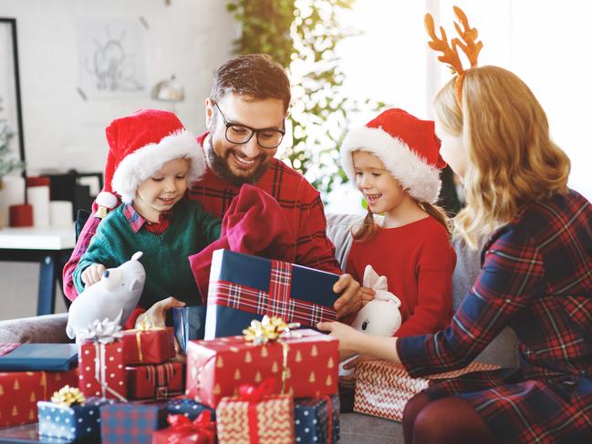 Six different christmas presents is on a table. A christmas tree is in the background.