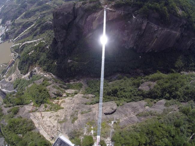 Sunlight reflects off a glass-bottomed suspension bridge as seen from the air in a scenic zone in Pingjiang county in southern China's Hunan province Thursday, Sept. 24, 2015. The bridge, about 300 meters (984 feet) long and 180 meters (590 feet) above the valley floor, opened to visitors on Thursday for the first time since its conversion from a regular suspension bridge was completed. (Chinatopix Via AP) CHINA OUT