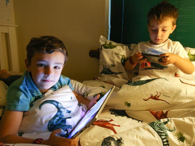 Angus, 6, and Sebastian, 4, on their devices at home in Malvern East, Melbourne. Picture: Ian Currie