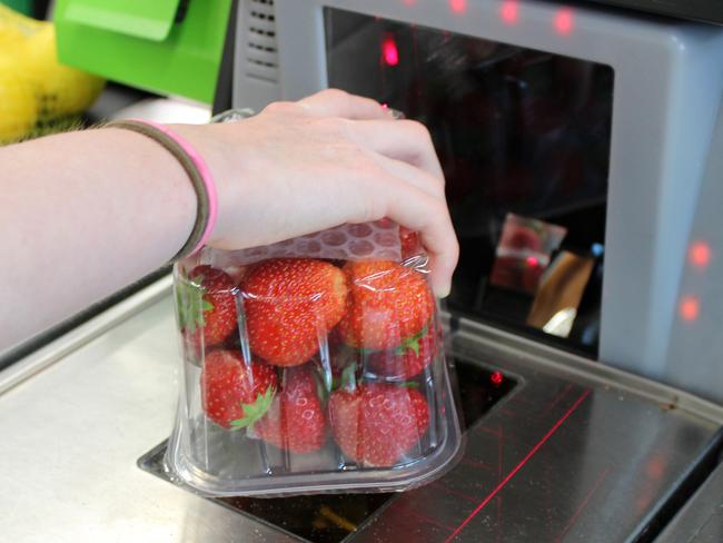 Photo showing a girl scanning her shopping (including fresh fruit / organic strawberries) at a self-service supermarket checkout till (also known as 'Self Checkouts' and 'Semi Attended Customer Activated Terminals' - SACAT. Self-service checkouts are quickly becoming commonplace in large supermarkets, reducing staff costs and replacing the need for cashiers.