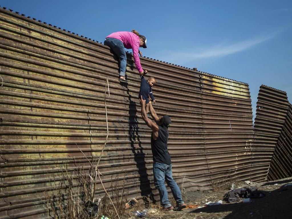 A group of Central American migrants climb the border fence between Mexico and the United States, near El Chaparral border crossing, in Tijuana, Baja California State, Mexico. Hundreds of migrants attempted to storm a border fence separating Mexico from the US amid mounting fears they will be kept in Mexico while their applications for asylum are processed. An AFP photographer said the migrants broke away from a peaceful march at a border bridge and tried to climb over a metal border barrier in the attempt to enter the United States. Picture: AFP