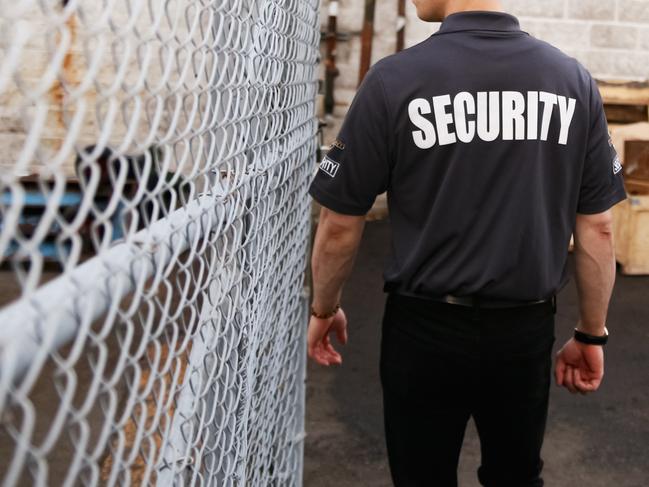 A security guard is patrolling in a fenced commercial area.