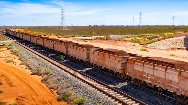 A freight train carrying iron ore travels along a rail track towards Port Hedland, Australia, on Monday, March 18, 2019. A two-day drive from the nearest big city, Perth, Port Hedland is the nexus of Australias iron-ore industry, the terminus of one of Australias longest private railways that hauls ore about 400 kilometers (250 miles) from the mines of BHP Group and Fortescue Metals Group Ltd. The line ran a record-breaking test train weighing almost 100,000 tons that was more than 7 kilometers long in 2001, and even normal trains haul up to 250 wagons of ore. Photographer: Ian Waldie/Bloomberg via Getty Images