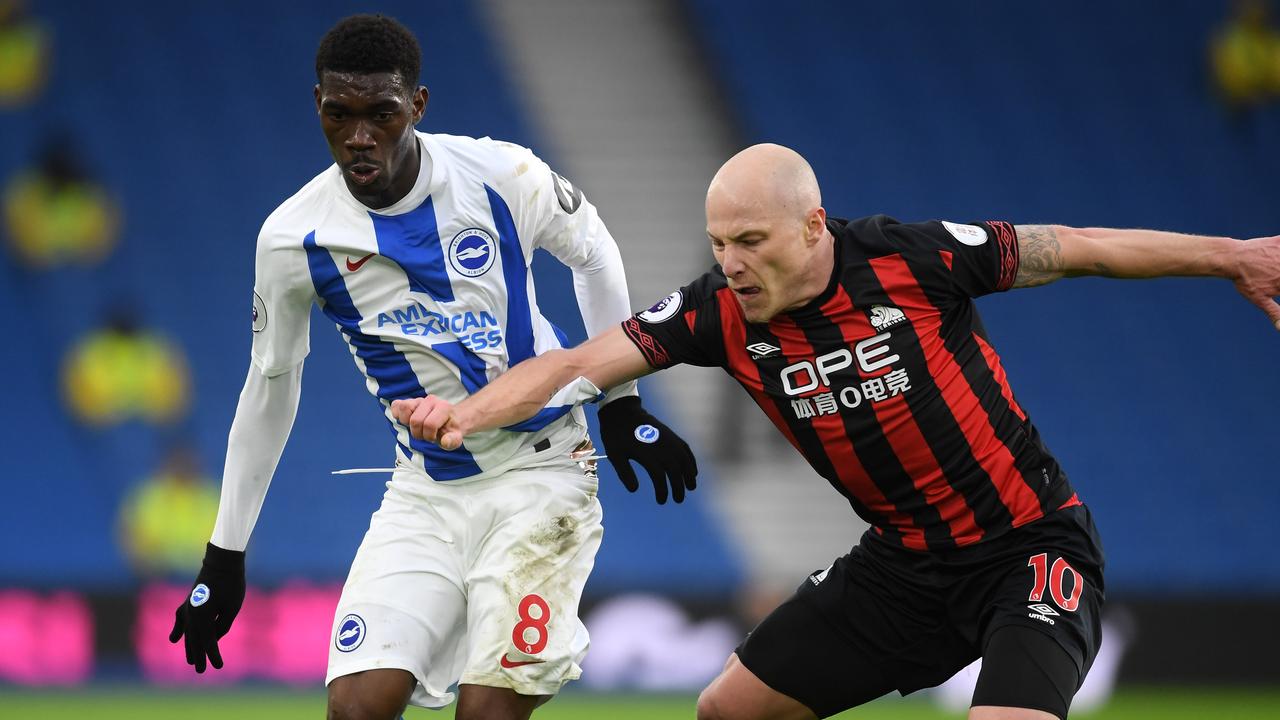 Yves Bissouma of Brighton and Hove Abion is challenged by Aaron Mooy of Huddersfield Town