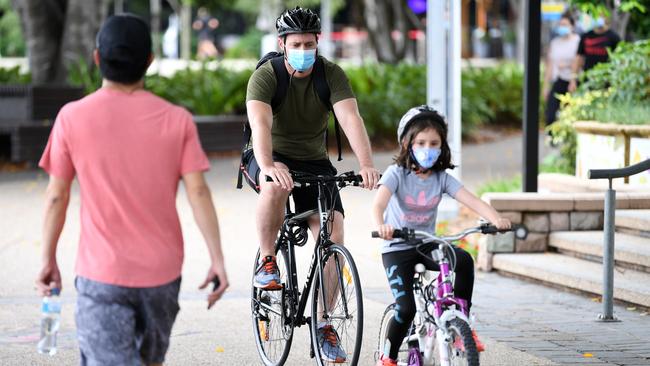 A father and daughter wear face masks as they ride their bikes during the three day Greater Brisbane lockdown. Picture: NCA NewsWire/Dan Peled.