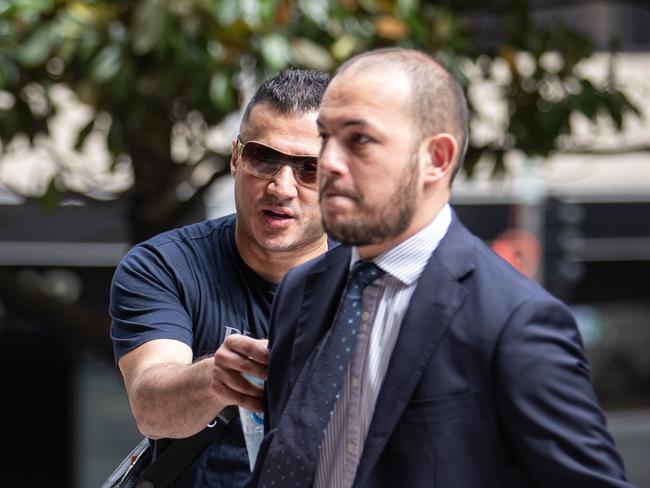 Nedal Haouchar (wearing glasses), pictured attempting to hide behind his lawyer, Talal Krayem, outside Sydney’s Downing Centre Local Court on Wednesday. Picture: Julian Andrews