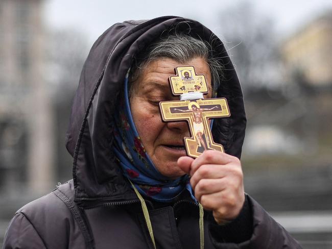 A woman holds a cross as she prays at Independence Square in Kyiv on the morning of Russia’s invasion. Picture: AFP