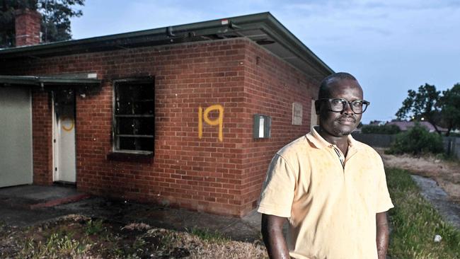 Nelson St Kilburn resident, father of five and former child soldier Mr Bol Bol outside a burnt Trust house. Picture: Brenton Edwards