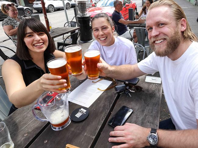 MELBOURNE, AUSTRALIA - NewsWire Photos 22 OCTOBER 2021 : Sisters Amy and Alice Whitfield enjoy a beer with Dane Thorne outside the Builders Arms Hotel in Fitzroy as Melbourne eases out of lockdown. Picture : NCA NewsWire / Ian Currie