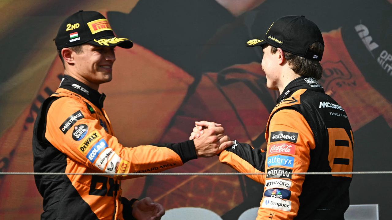 TOPSHOT - McLaren's Australian driver Oscar Piastri (R) is congratulated by McLaren's British driver Lando Norris on the podium after the Formula One Hungarian Grand Prix at the Hungaroring race track in Mogyorod near Budapest on July 21, 2024. (Photo by Attila KISBENEDEK / AFP)