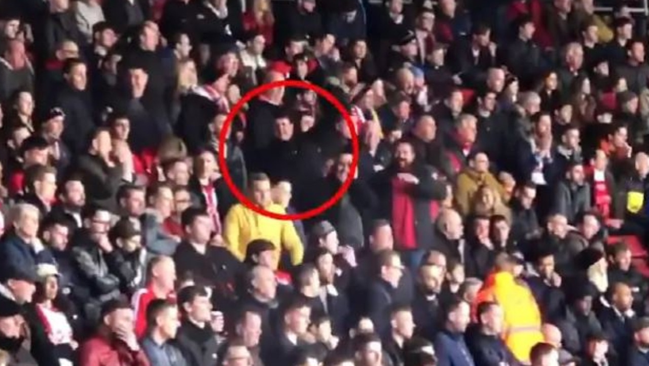A football fan stretches his arms out like an aeroplane.