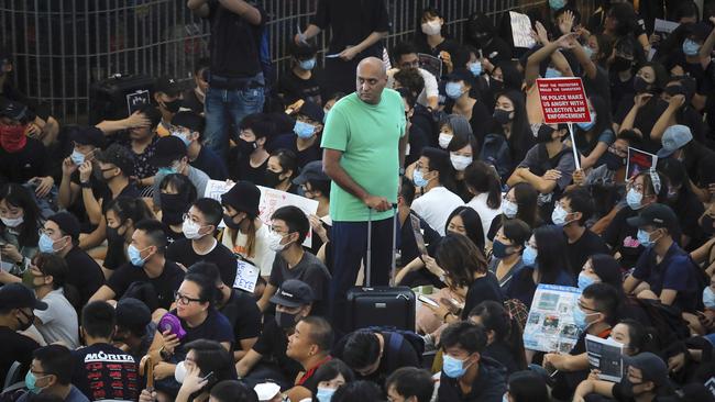 A traveller stands amidst protesters during in Hong Kong airport. Picture: AP