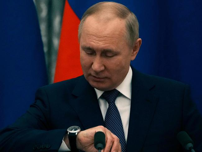 Russian President Vladimir Putin checks his watch before a press conference with the French President. Picture: AFP