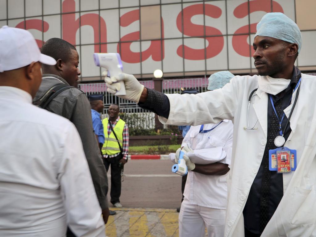 A health worker checks people's temperatures as they disembark a plane at the airport in Kinshasa, Congo. Picture: AP