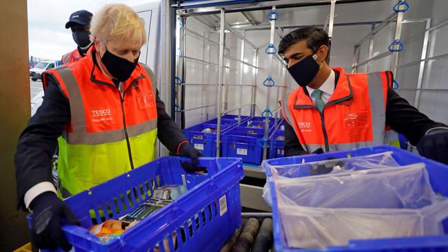 Britain’s Prime Minister Boris Johnson, left, Chancellor of the Exchequer Rishi Sunak load a delivery van during a visit to a supermarket distribution centre in London. Picture: AFP