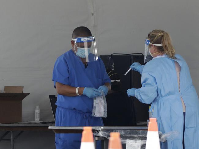 Healthcare workers put a vial containing a test swab into a bag after testing a driver at a drive-through coronavirus testing site in Florida. Picture: AP