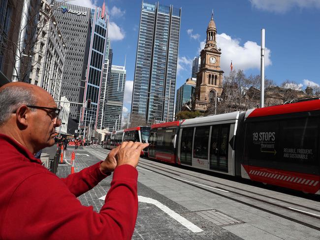 A pedestrian pauses for a picture of the new light rail. Picture: Brett Costello