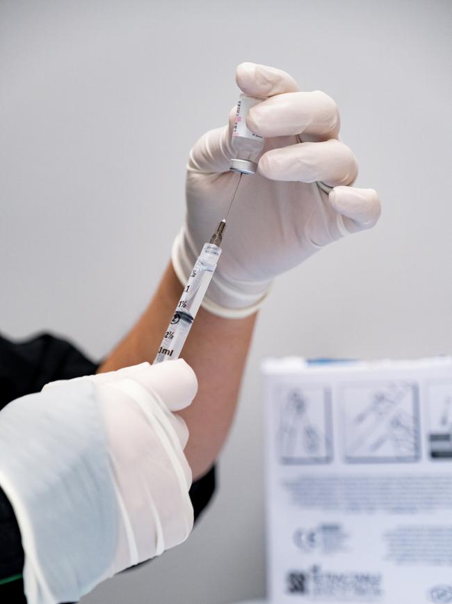 Close up of a nurses gloved hands as she carefully preps a syringe with the Covid-19 Vaccine.