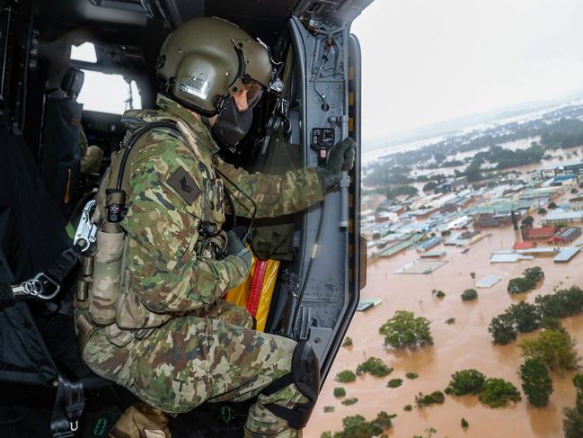 A handout photo taken on February 28 and released on March 3, 2022 shows Australian Army aircrewman Sergeant Rick Scott from the School of Army Aviation surveying flood waters from an MRH-90 Taipan helicopter over the northern New South Wales city of Lismore during Operation Flood Assist 2022. (Photo by Bradley RICHARDSON / Australian Defence Force / AFP) / ----EDITORS NOTE ----RESTRICTED TO EDITORIAL USE MANDATORY CREDIT " AFP PHOTO / AUSTRALIAN DEFENCE FORCE" NO MARKETING NO ADVERTISING CAMPAIGNS - DISTRIBUTED AS A SERVICE TO CLIENTS