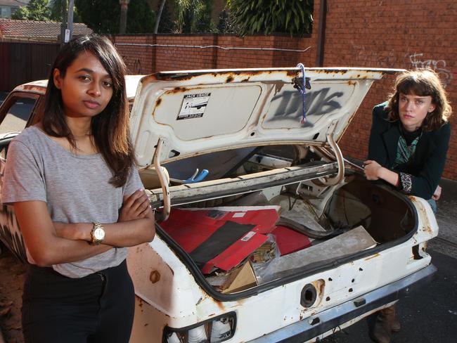 Shyama Sri and Isabelle Whitington next to an abandoned car which is being filled with rubbish. Picture: Robert Pozo