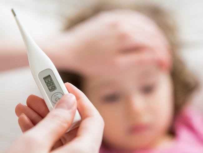 Close-up thermometer. Mother measuring temperature of her ill kid. Sick child with high fever laying in bed and mother holding thermometer. Hand on forehead.