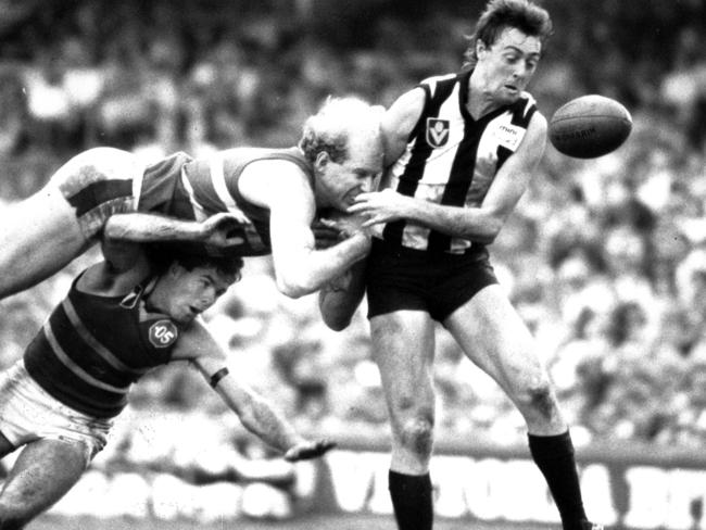 Simon Beasley crashes over the top of Ron James and Magpie Michael McGuane.