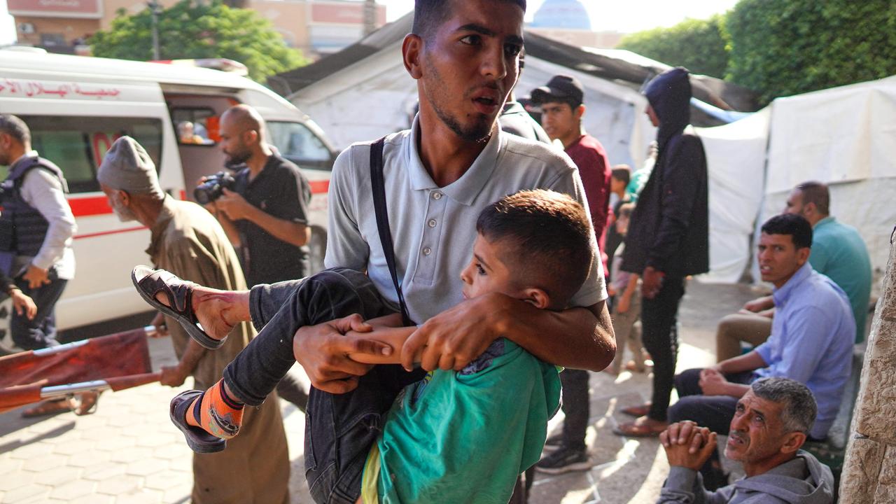 A Palestinian man rushes a child into a hospital in Deir el-Balah in the central Gaza Strip following Israeli bombardment.