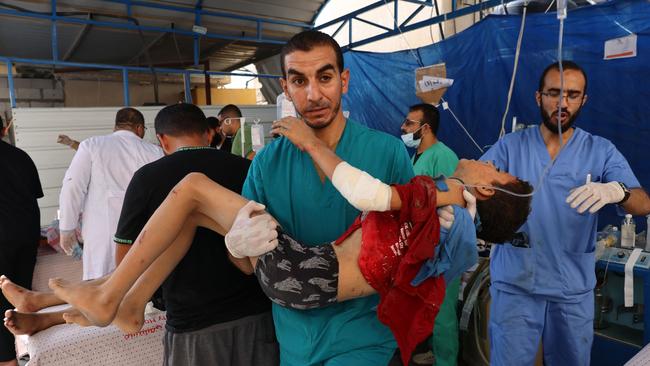 A medico carries an injured boy in Rafah. Picture: AFP