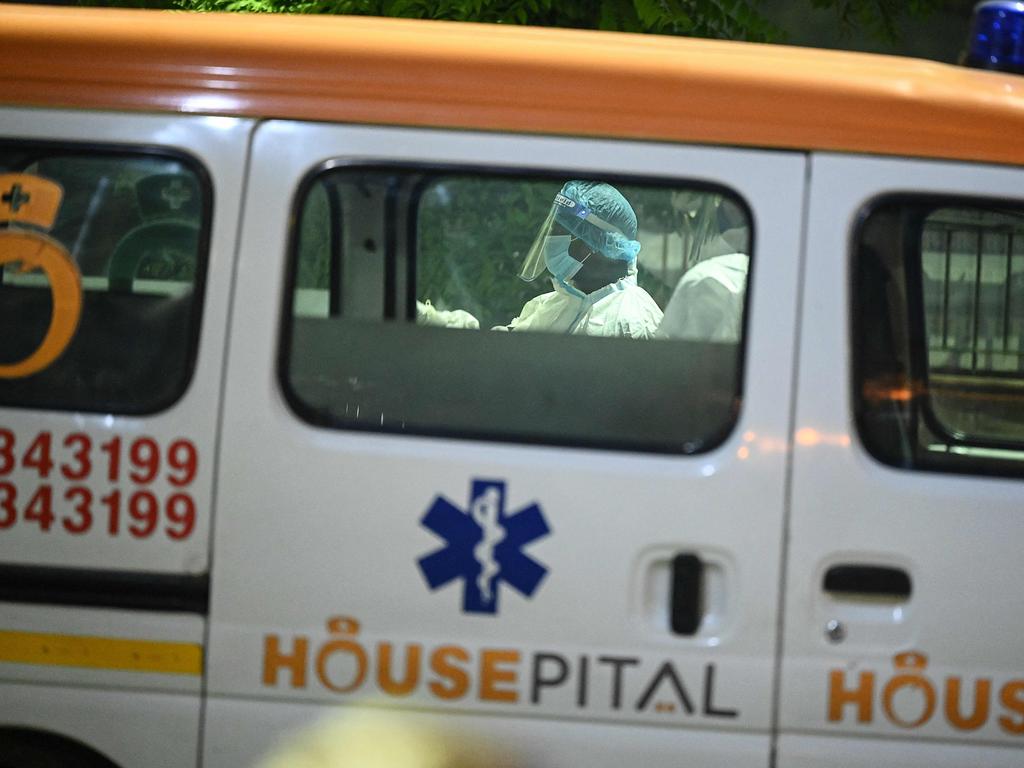 Crematorium staff members stand behind ambulances carrying bodies. Picture: Sajjad Hussain/AFP