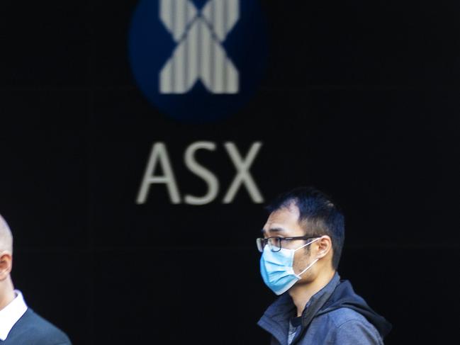 SYDNEY, AUSTRALIA - MARCH 13: A man in a mask is seen in front of The Australian Stock Exchange logo on March 13, 2020 in Sydney, Australia. The ASX200 plunged more than 7 percent in the first 15 minutes of trade on Friday, amid fears over the spread of COVID-19. The Australian sharemarket fall follows the worst day of trading on Thursday, which saw the worst losses since the Global Financial Crisis. (Photo by Jenny Evans/Getty Images)